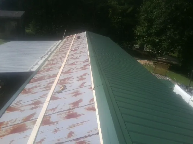 Old rusted panels beside newly installed green metal roofing — Wind Damage Roof Repair by Roofing Brothers in Alexandria